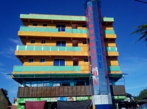 Un immeuble à plusieurs étages, doté de balcons, sur lequel on peut lire l’inscription « Accordia », et dont le rez-de-chaussée est occupé par divers commerces.