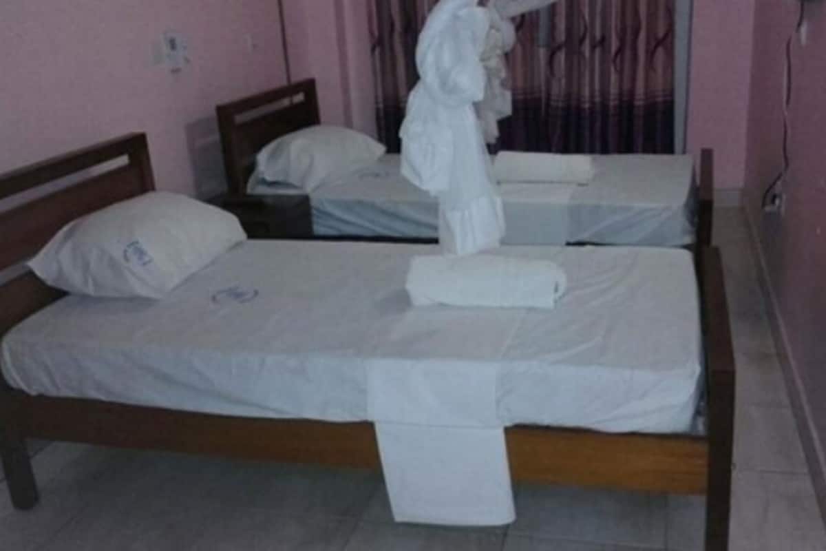 A room with three single beds, each with white linens and pillows.