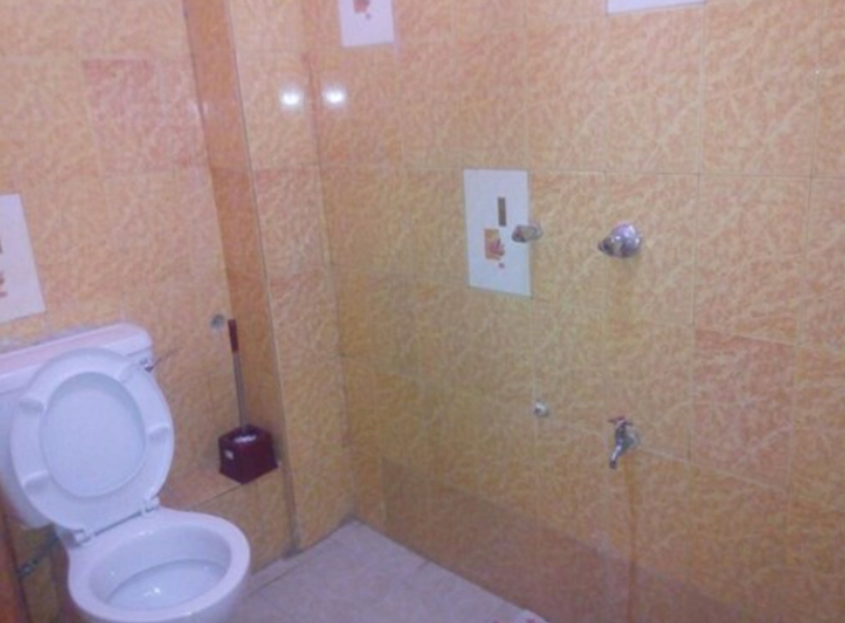 A small bathroom with a toilet, a hand dryer, and a paper dispenser on the wall.