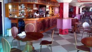 A bar area with a bartender, checkered floor, and wooden furniture. - Check Point Inn Mombasa (Mombasa)