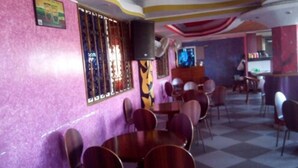 A restaurant interior with pink walls, checkered flooring, and a bar area with stools. - Check Point Inn Mombasa (Mombasa)