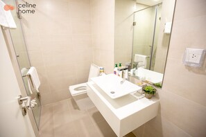 A modern bathroom with a glass shower enclosure, a white sink, and a toilet. - Celine Home Millenium (Ho Chi Minh City)