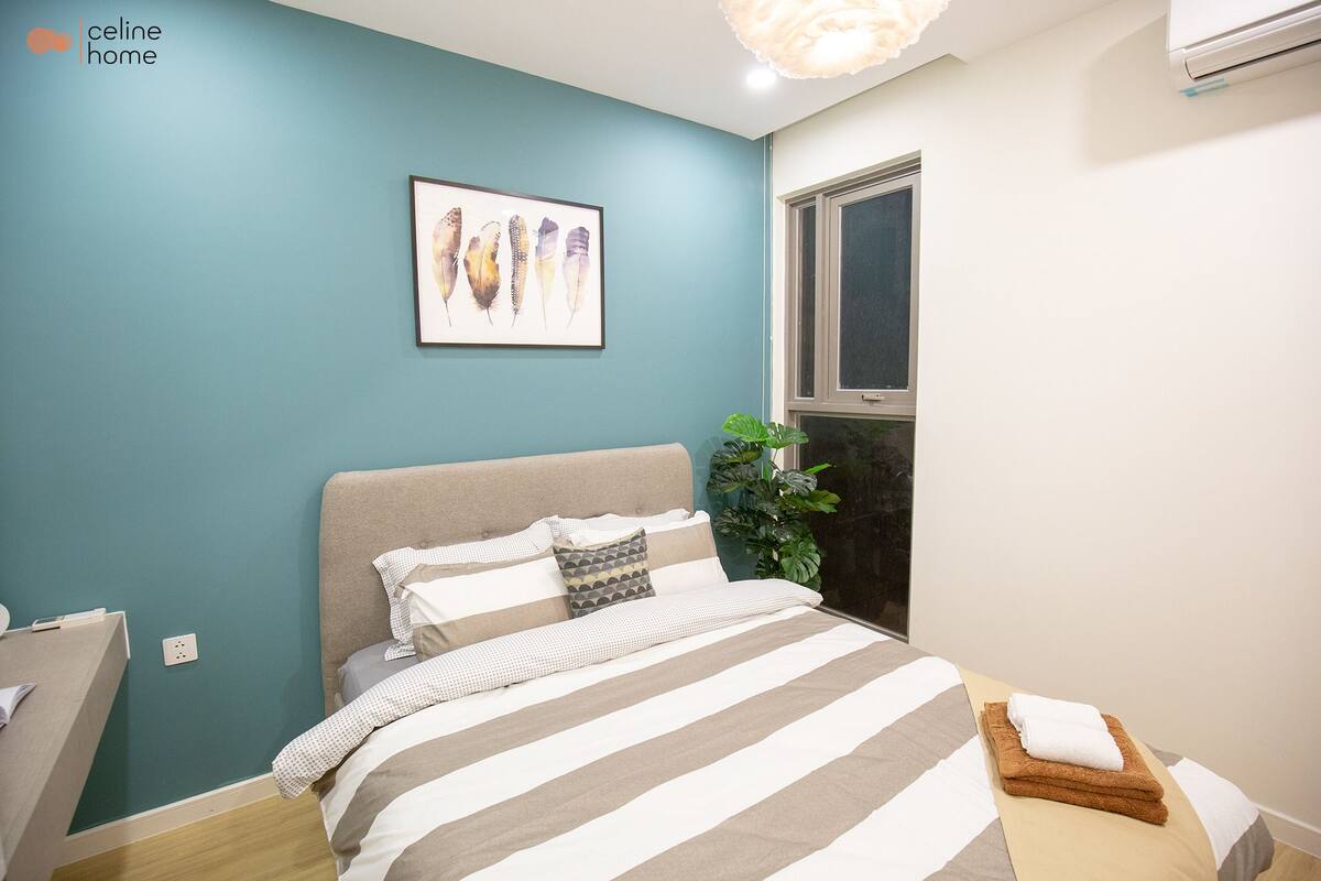 A bedroom with a bed, a window, and a plant.