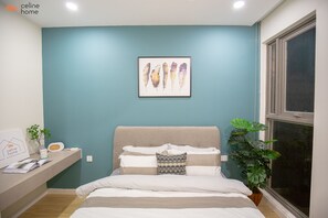 A bedroom with a teal wall, a framed feather artwork, a bed with striped bedding, a bedside plant, and a window with a view. - Celine Home Millenium (Ho Chi Minh City)