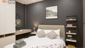 A modern bedroom with a bed, pillows, a bedside table, a wall-mounted shelf, and a framed picture. - Celine Home Millenium (Ho Chi Minh City)