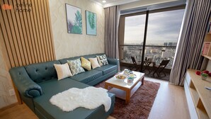 Un salon moderne avec un canapé vert, un plaid blanc et moelleux, et une table basse agrémentée d’objets décoratifs.