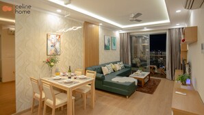 Un salon moderne avec un coin repas, un canapé vert et une vue sur la ville la nuit.