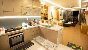 Une cuisine moderne dotée d’appareils électroménagers intégrés, un coin repas avec un canapé et une vue sur la ville la nuit.