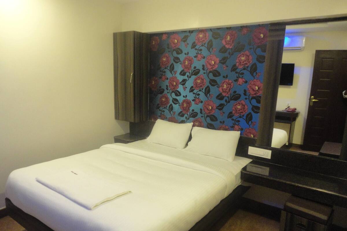 A hotel room with a bed, a desk, and a mirror.