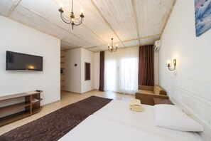 Une chambre à coucher avec un lit, une télévision, un lustre, un escalier et un tableau accroché au mur.