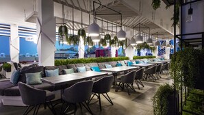 A modern outdoor dining area with multiple tables and chairs, hanging pendant lights, and potted plants. - GoodZone Club Hotel Zatoka (Zatoka)