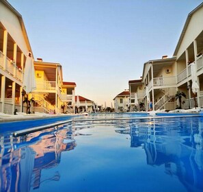 Une piscine à l’eau d’un bleu limpide, entourée d’immeubles à plusieurs étages dotés de balcons et d’espaces de détente en plein air.