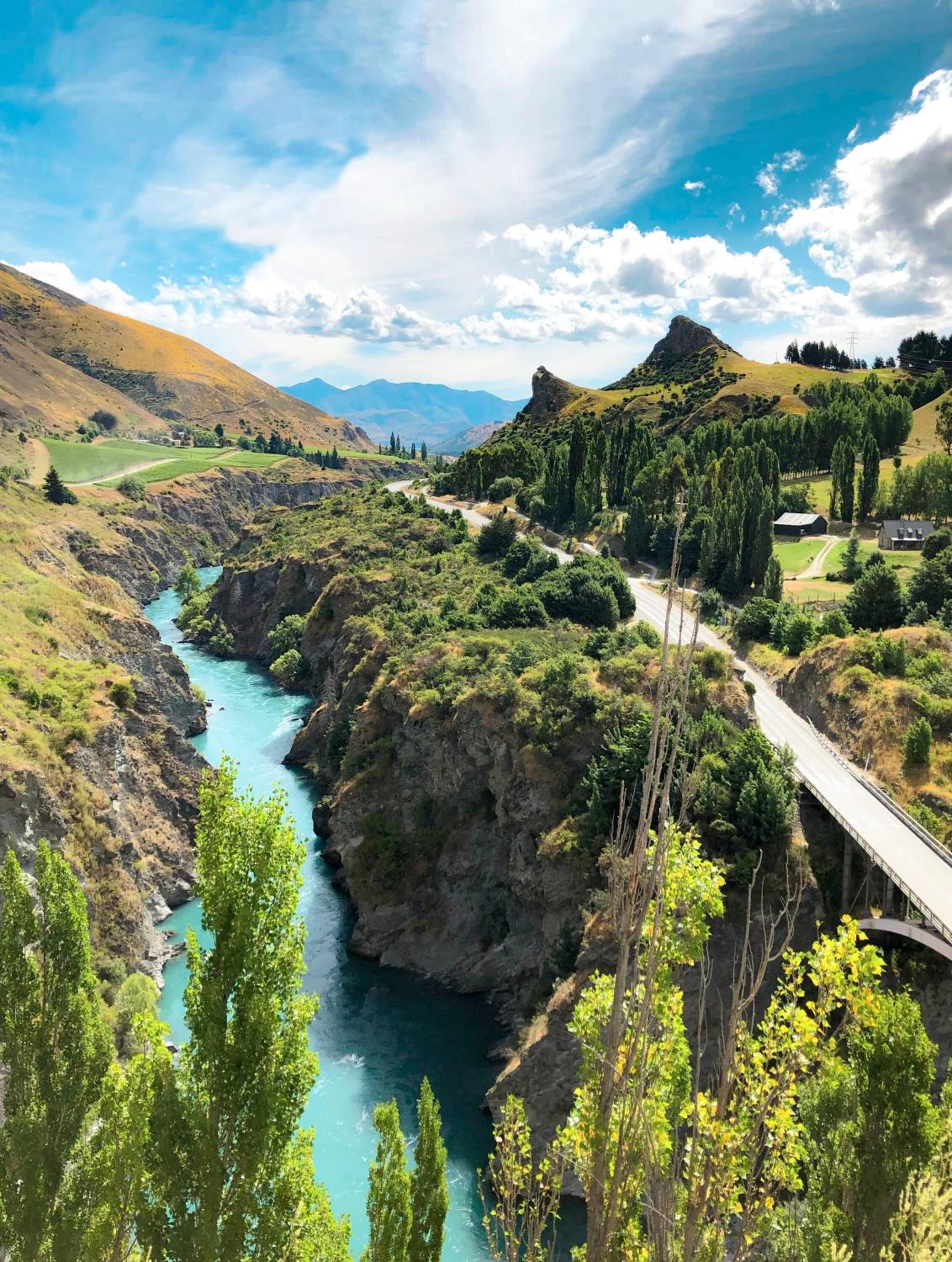 Ein Fluss fließt durch ein Tal, mit einer Brücke und einer Straße.