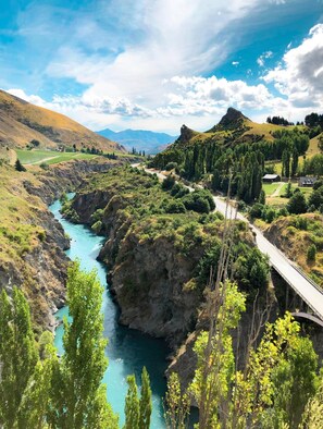 A river flowing through a valley with a bridge and a road.