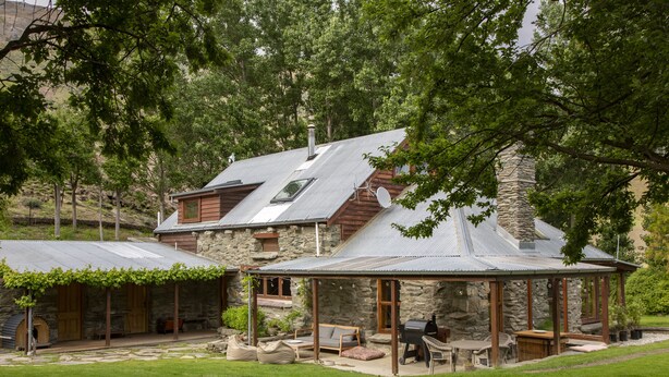 Una casa de piedra con un porche cubierto, mobiliario exterior y una zona de barbacoa.