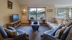 Una sala de estar con un ventanal grande, un televisor, una mesa de centro y dos sofás.