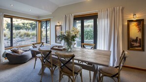 Comedor con mesa de madera, seis sillas y un florero con flores.