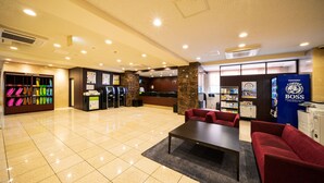 A hotel lobby with a reception desk, vending machines, a coffee machine, and a seating area with a table and chairs. - Sanco INN Numazu-ekimae (Numazu)