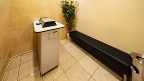 A reception desk with a plant beside it, a bench, and a trash bin. - Sanco INN Numazu-ekimae (Numazu)