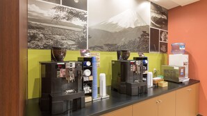 A coffee station with two espresso machines, a water dispenser, and a stack of disposable cups. - Sanco INN Numazu-ekimae (Numazu)
