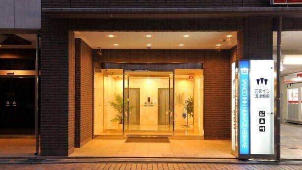 A hotel entrance with a glass door, a reception desk, and a signboard with Japanese characters. - Sanco INN Numazu-ekimae (Numazu)