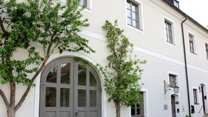 A building with a large arched door, multiple windows, and a small staircase leading to an upper level. - Ultra Alpes (Rottenbuch)