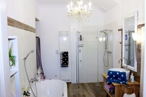 A modern bathroom with a bathtub, shower, and vanity. - Ultra Alpes (Rottenbuch)