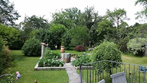 A garden with a stone pathway, various plants, and a bird feeder. - Ultra Alpes (Rottenbuch)