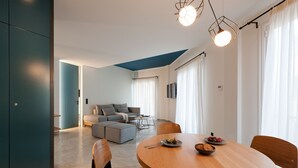 A modern living room with a sofa, a dining table with chairs, and a kitchen area in the background. - Syntagma Square Modern Apartments (Athens)