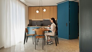 A modern kitchen with wooden cabinets, a dining table with chairs, and pendant lighting. - Syntagma Square Modern Apartments (Athens)