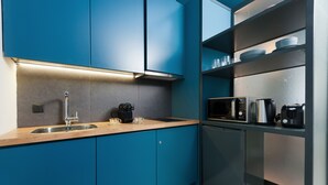 A modern kitchen with blue cabinets, a stainless steel sink, and a built-in microwave. - Syntagma Square Modern Apartments (Athens)