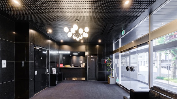 A reception area with a reception desk, a plant, and a bench. - Tabist THE GREEN ASAHIKAWA (Asahikawa)