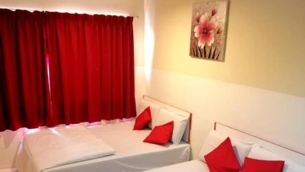 A hotel room with two single beds, red pillows, a painting on the wall, and red curtains. - My Home Hotel - Setapak (Kuala Lumpur)