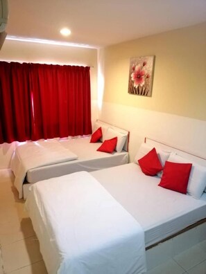 Een hotelkamer met twee enkele bedden, rode kussens, een rood gordijn en een wanddecoratie.