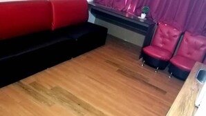 A living room with a red sofa, a black couch, and a red chair. There is a television on a stand and a small table with a plant. - My Home Hotel - Setapak (Kuala Lumpur)