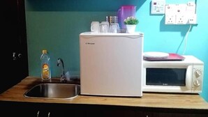 A compact kitchen with a white refrigerator, a microwave, a sink, and a small countertop. - My Home Hotel - Setapak (Kuala Lumpur)
