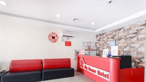 A hotel reception area with a red reception desk, black and red seating, a wall clock, and a stone-patterned wall. - My Home Hotel - Setapak (Kuala Lumpur)