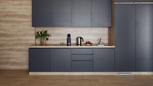 A modern kitchen with dark cabinetry, a wooden countertop, and a plant.