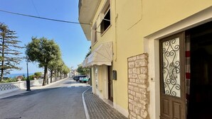 A street with a building featuring a stone wall, a metal gate, and a door with decorative glass. - N158 - Numana, sky-land sea view 150mt from the sea (Numana)
