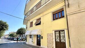 A two-story building with a yellow facade, a balcony on the upper floor, and a ground-floor entrance with a door and window. - N158 - Numana, sky-land sea view 150mt from the sea (Numana)