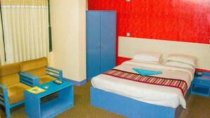 Una habitación de hotel con cama, armario azul, sofá y una mesita.