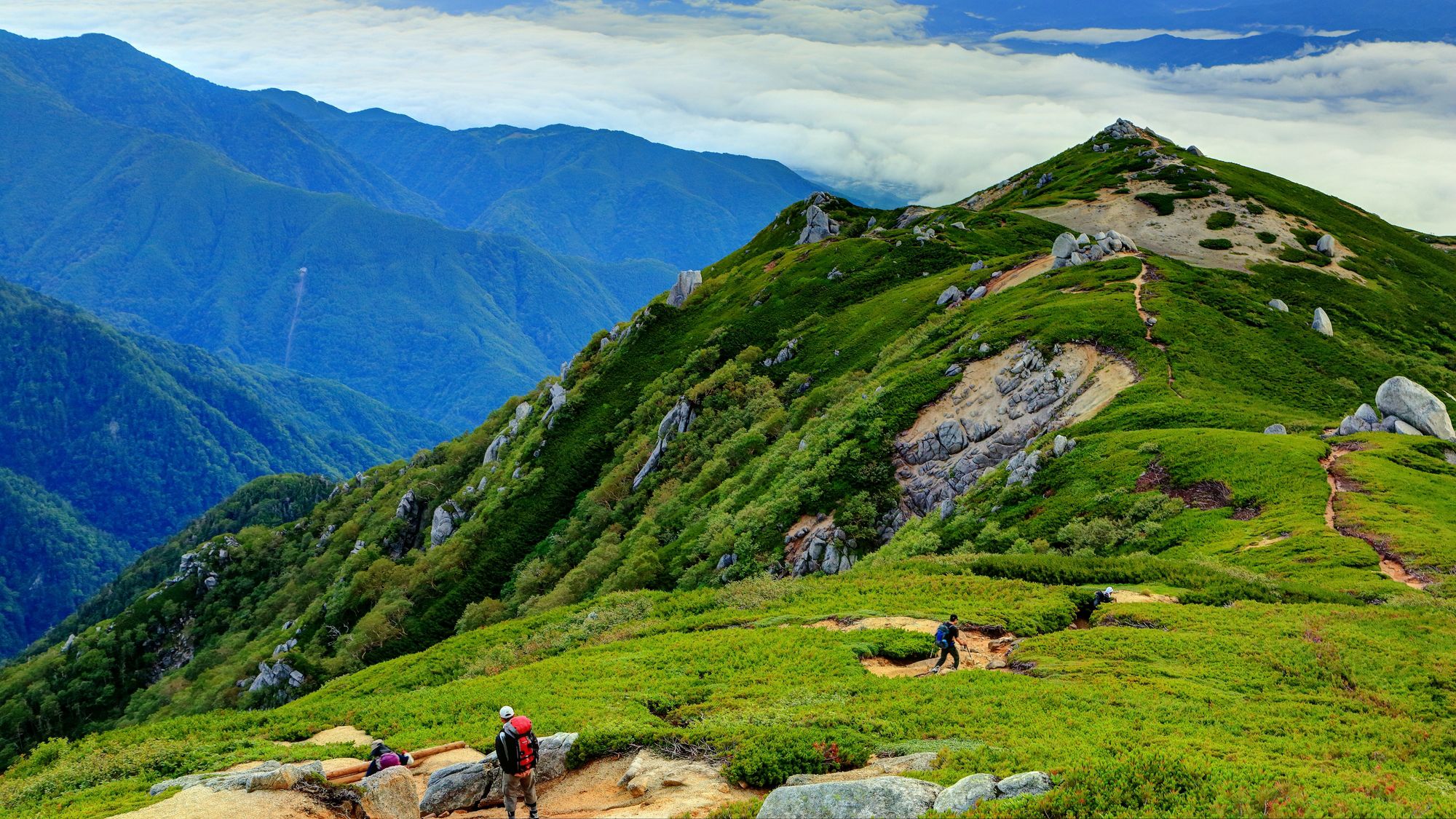 A mountainous landscape with hikers on a trail.