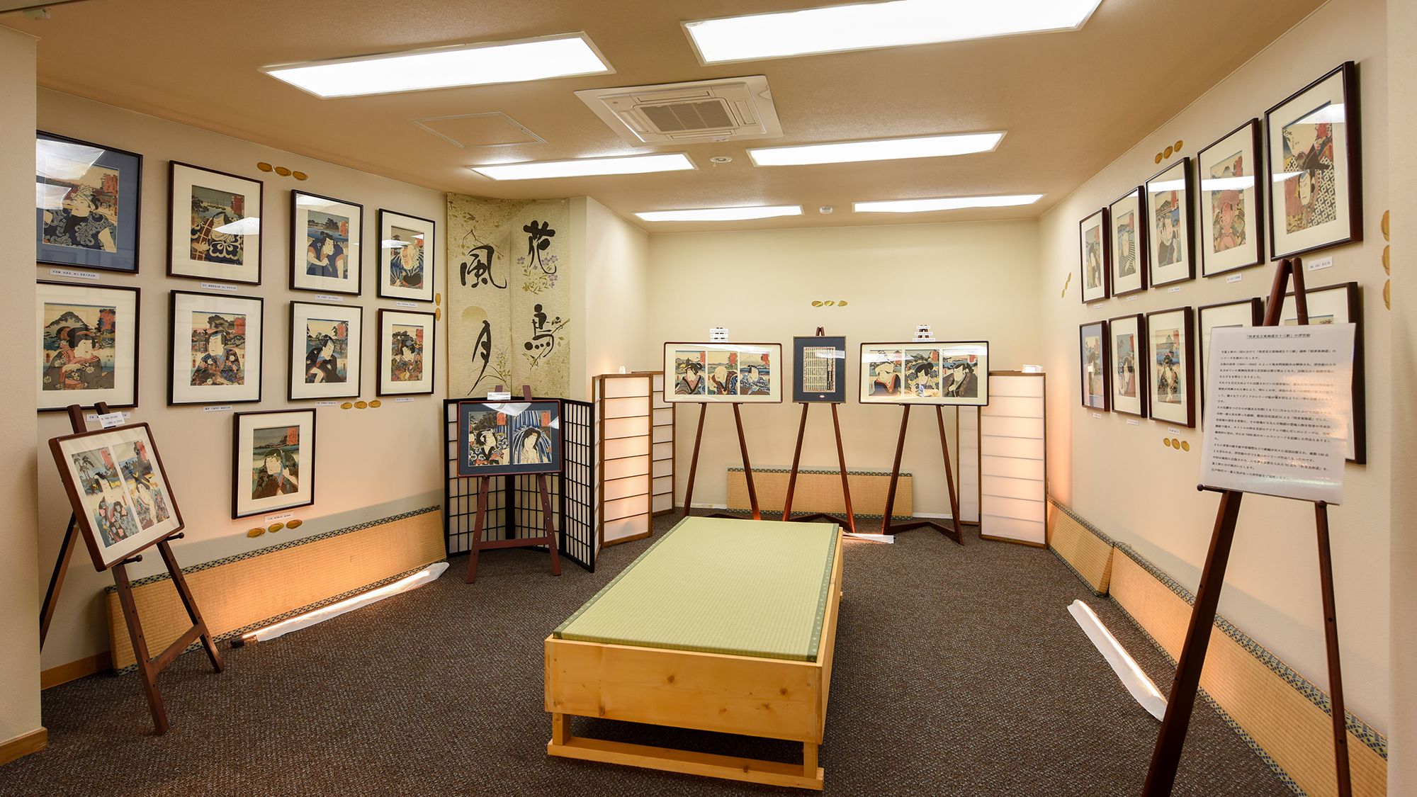A room with traditional Japanese artwork on the walls, a tatami mat floor, and a low wooden bed.