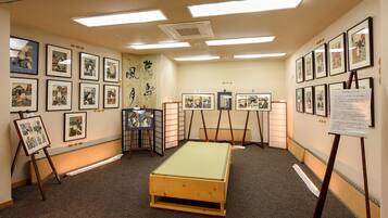 A room with traditional Japanese artwork on the walls, a tatami mat floor, and a low wooden bed.