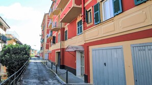 Una calle estrecha con edificios de color rojo y beige, balcones y una puerta de garaje azul.