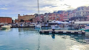 Un puerto deportivo con barcos amarrados, rodeado de edificios coloridos y un cielo despejado.