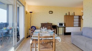 Un comedor con una mesa lista para cuatro personas, un sofá, un armario y un microondas.
