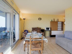 Ein Essbereich mit Tisch für vier Personen, einer Couch, einem Schrank und einer Mikrowelle.