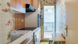 Una cocina compacta con armarios de madera, salpicadero de azulejos y un pequeño comedor con mesa y sillas.