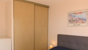Una habitación de hotel con cama, un amplio ventanal corredero y un cuadro enmarcado en la pared.